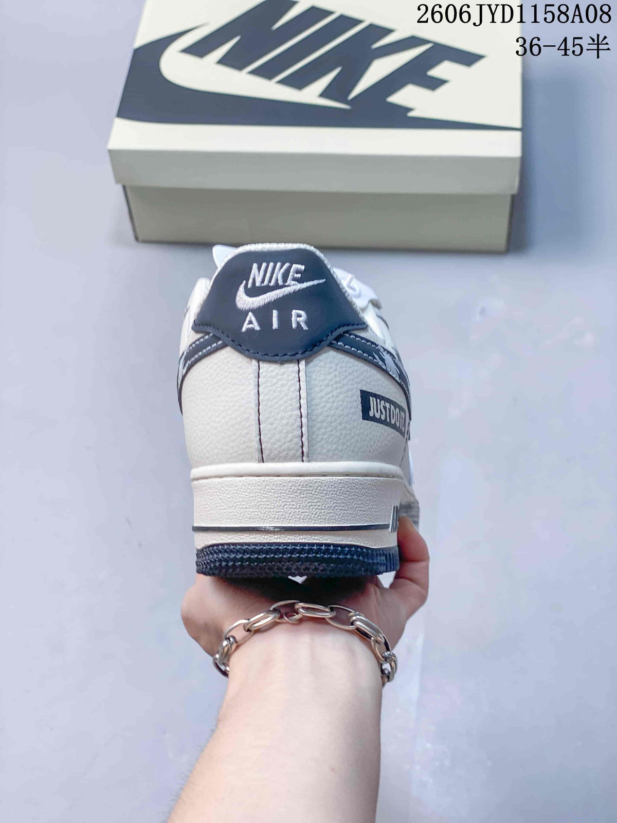 Rear view of the white sneaker with navy heel tab and decorative heel detail.