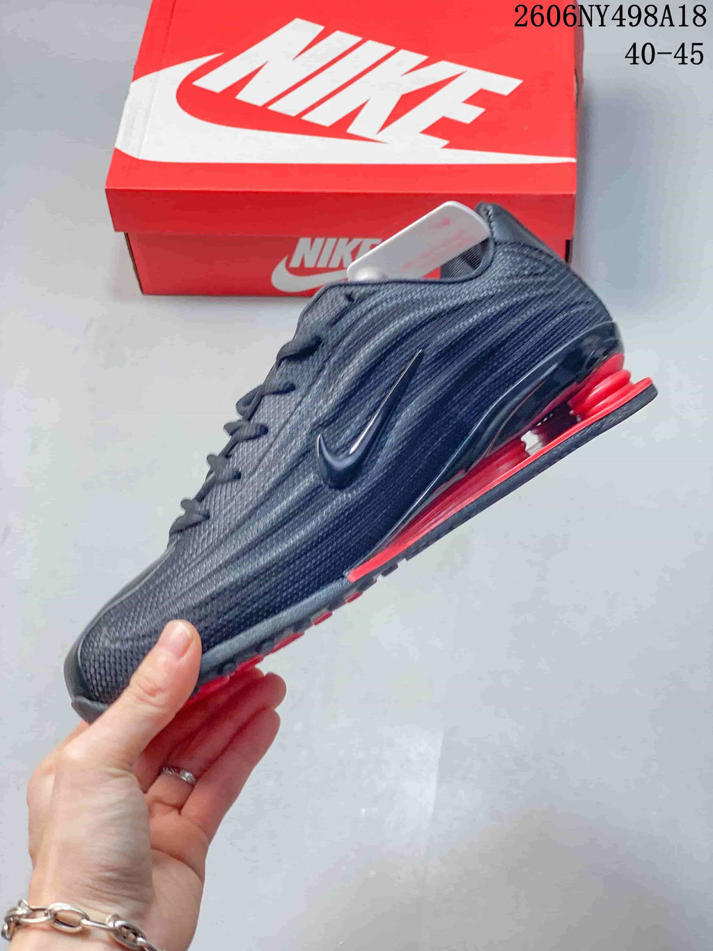 Side profile of a charcoal Nike Shox TL sneaker with red heel columns and a side Swoosh.