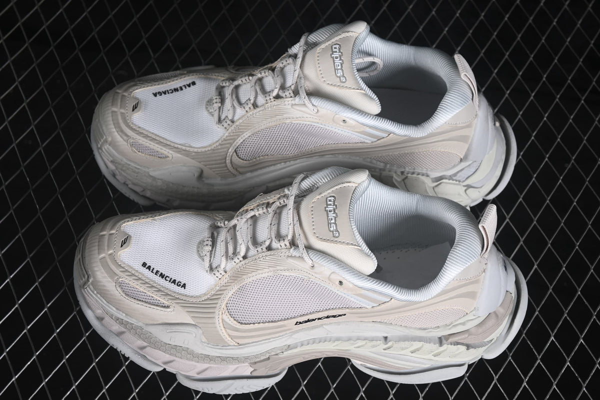 Angled overhead view of a pair of cream Balenciaga Triple S 2 sneakers with layered construction and padded collars.