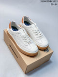White ECCO low-top sneakers with tan heel accents and gum-colored soles, shown on a box.