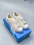 Pair of off-white Adidas Superstar II sneakers with shell toes and decorative lace accessories