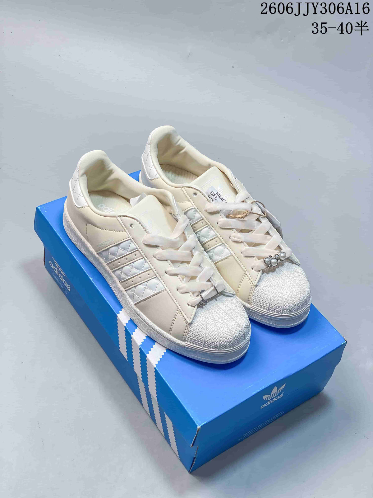 Pair of off-white Adidas Superstar II sneakers with shell toes and decorative lace accessories