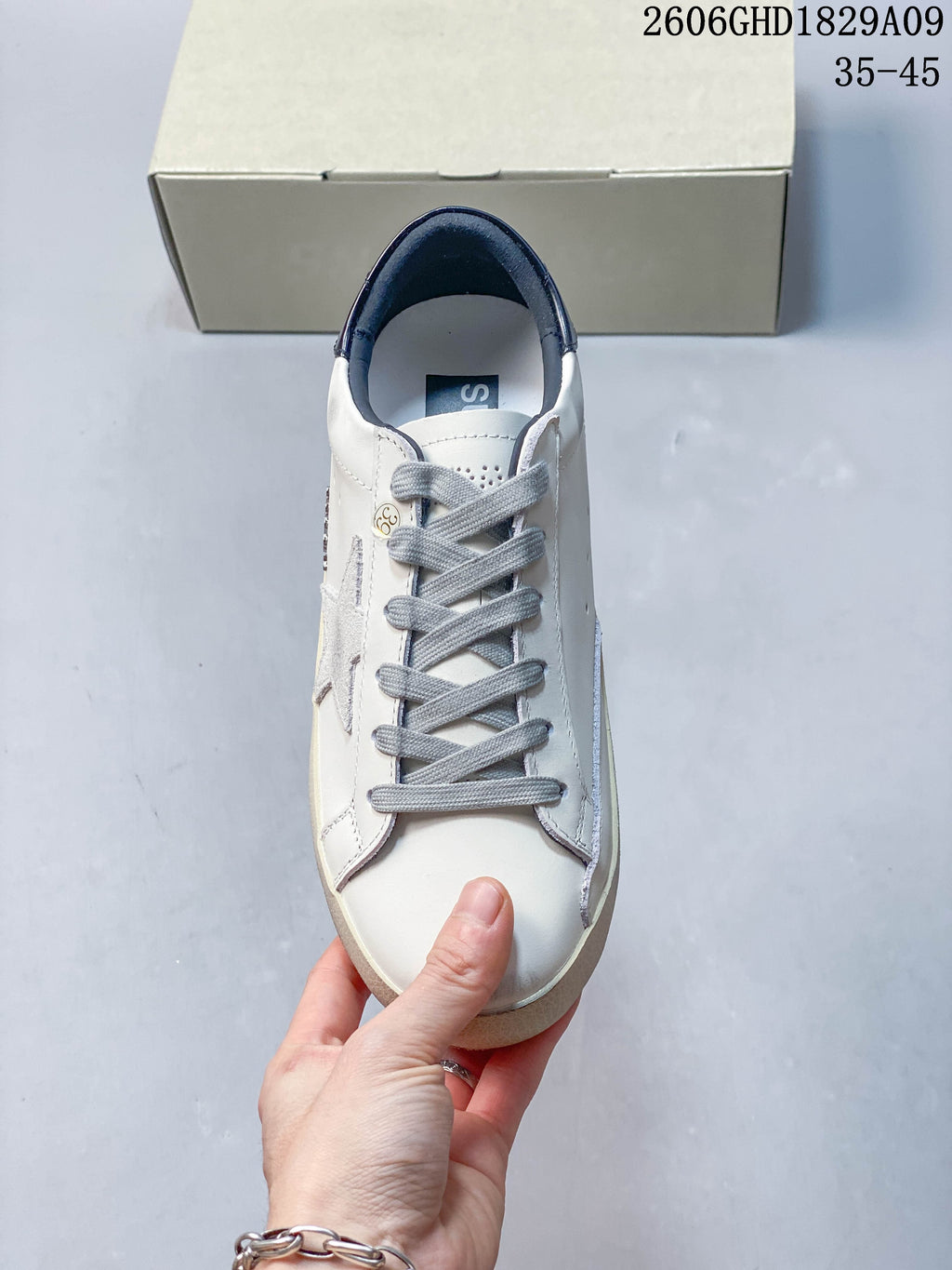 Front view of white sneaker with gray laces and dark blue lining