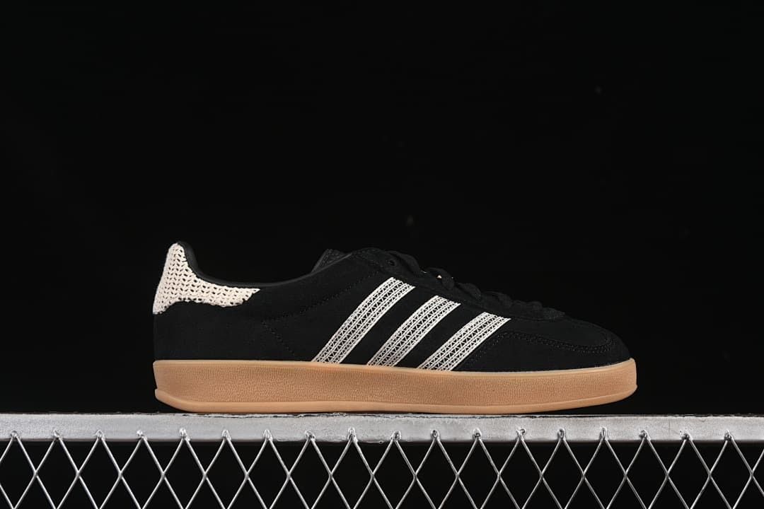 Side profile of the black sneaker with cream stripes and a gum-colored sole.