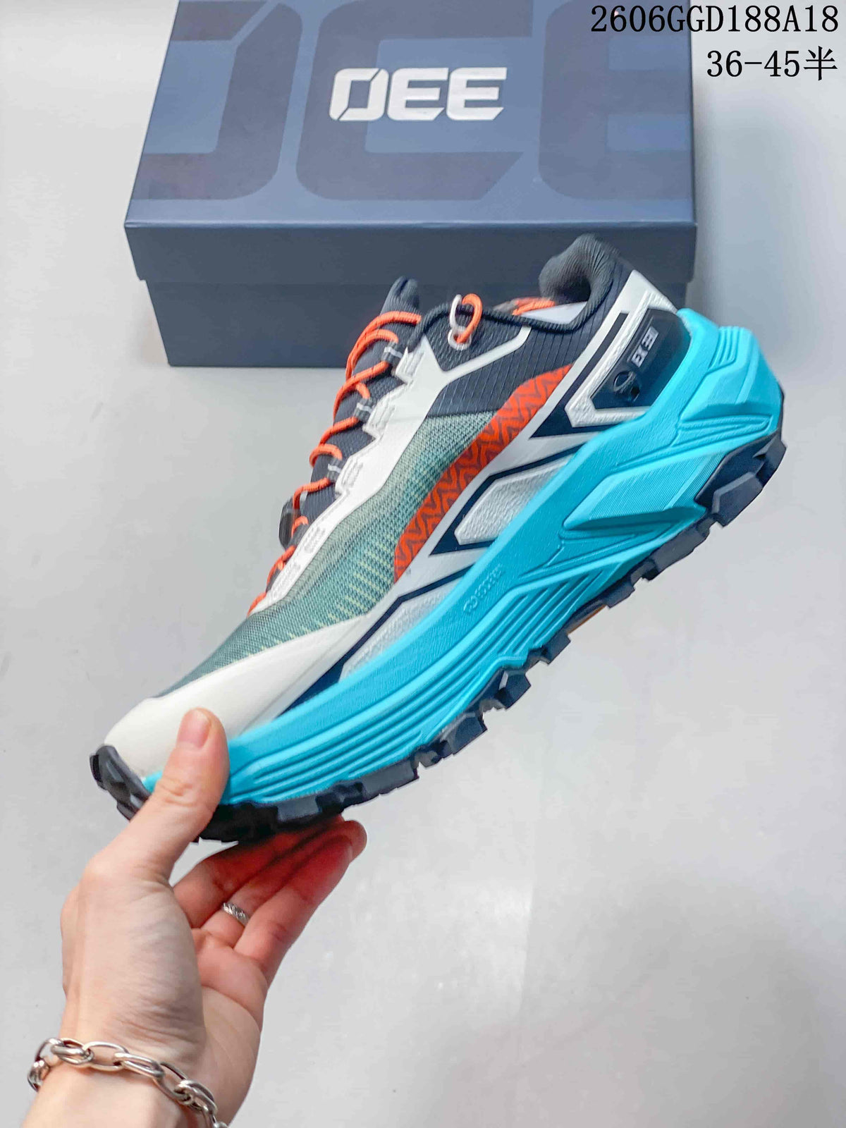 Side profile of the teal and gray trail shoe with orange accents