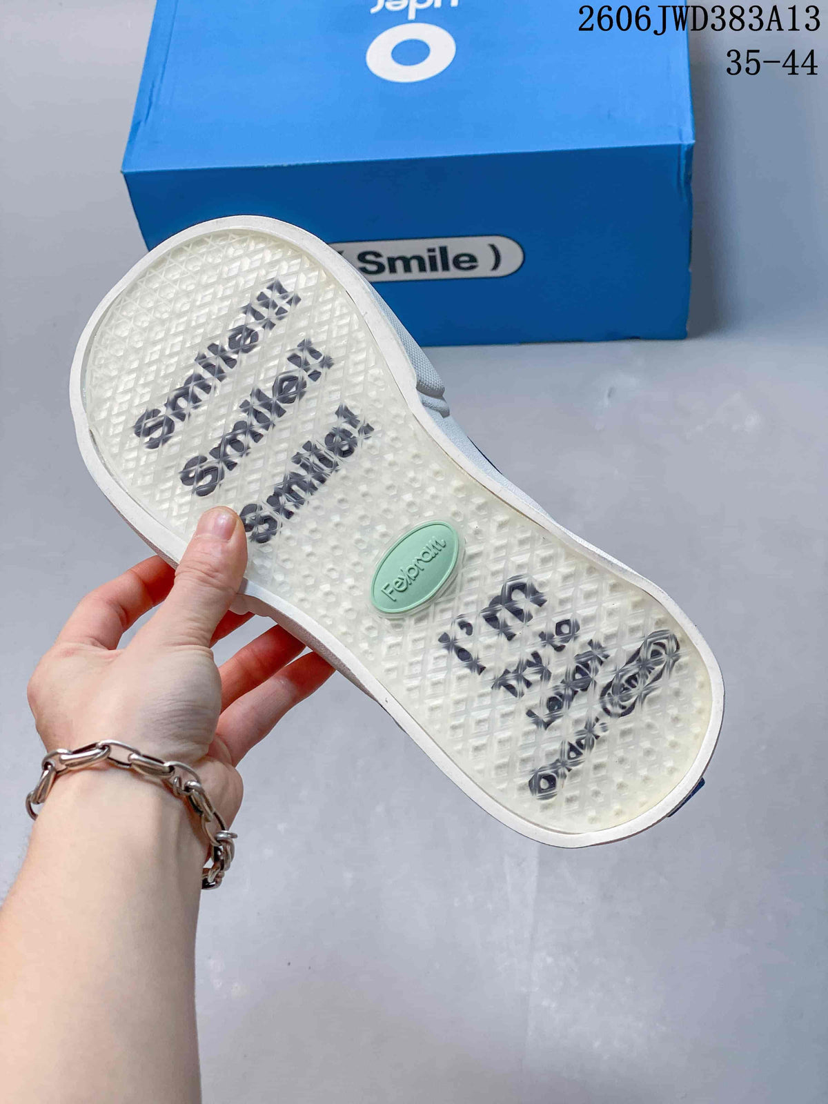 View of the sneaker outsole with patterned tread and branded detailing.