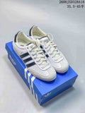 Pair of white adidas Originals Japan sneakers with dark stripes, shown on a blue shoebox