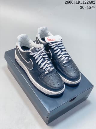 Pair of black Nike Air Force 1 sneakers on a box, showing perforated toe panels, white laces, and padded collars.