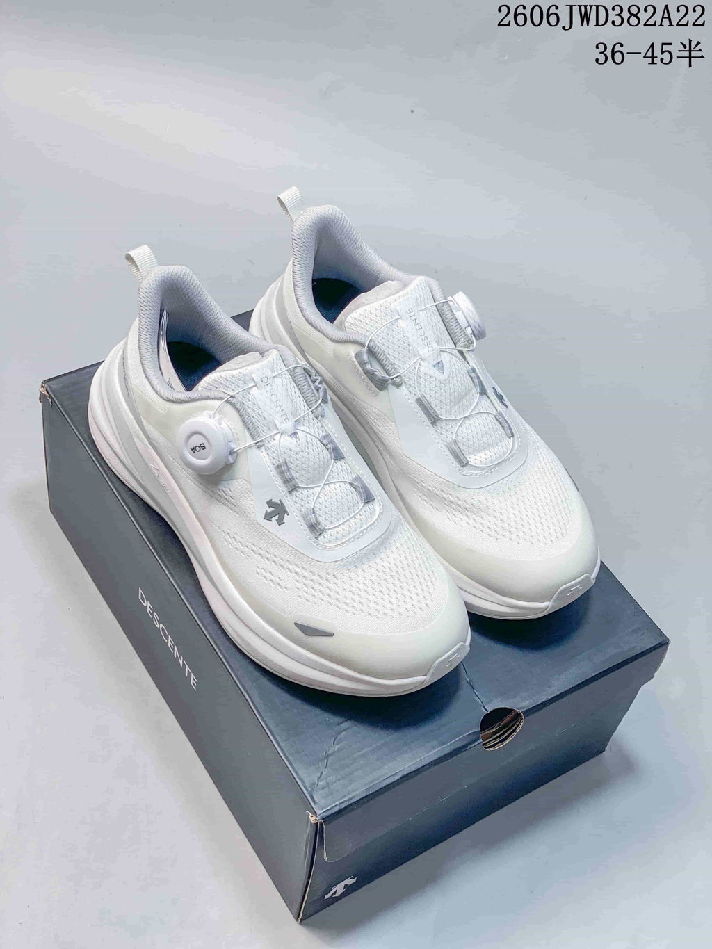 White DESCENTE running shoes with BOA dial closures, shown on a shoe box.
