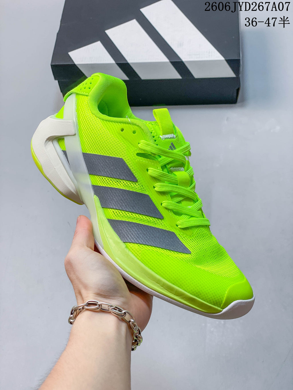 Side view of the bright yellow tennis shoe with gray stripes and a structured heel.