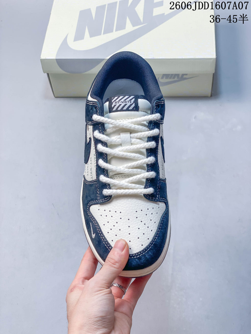 Top view of a navy and white low-top sneaker showing laces and a perforated toe