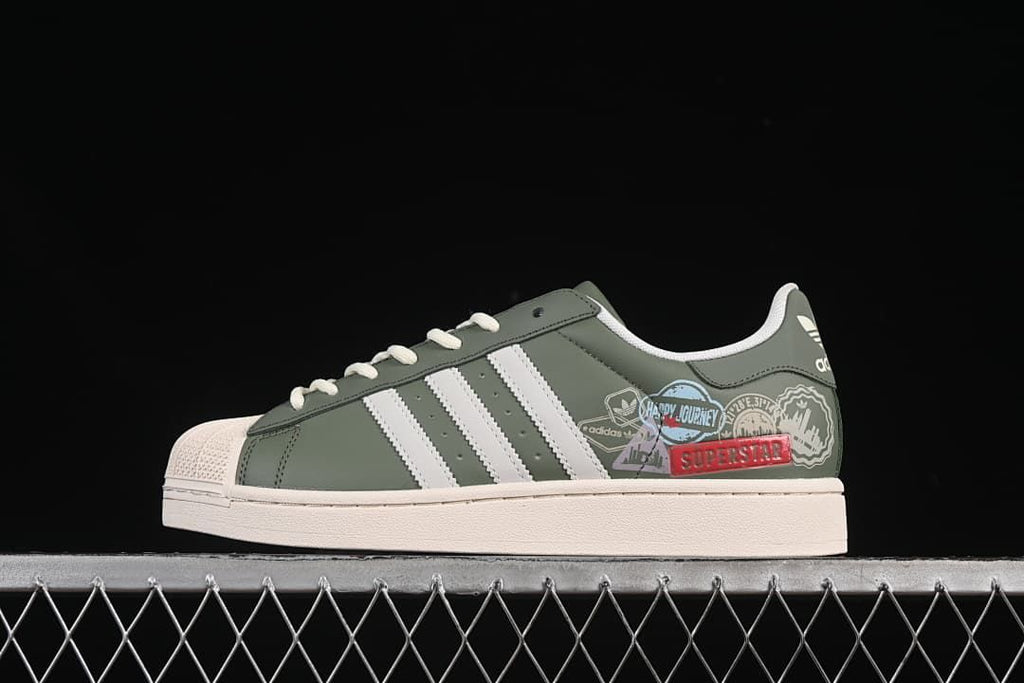 Side view of a green adidas Superstar II sneaker with white stripes, cream shell toe and printed side graphics.