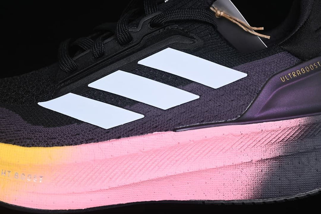 Close-up of the shoe's black and purple upper, white stripes, and pink midsole.