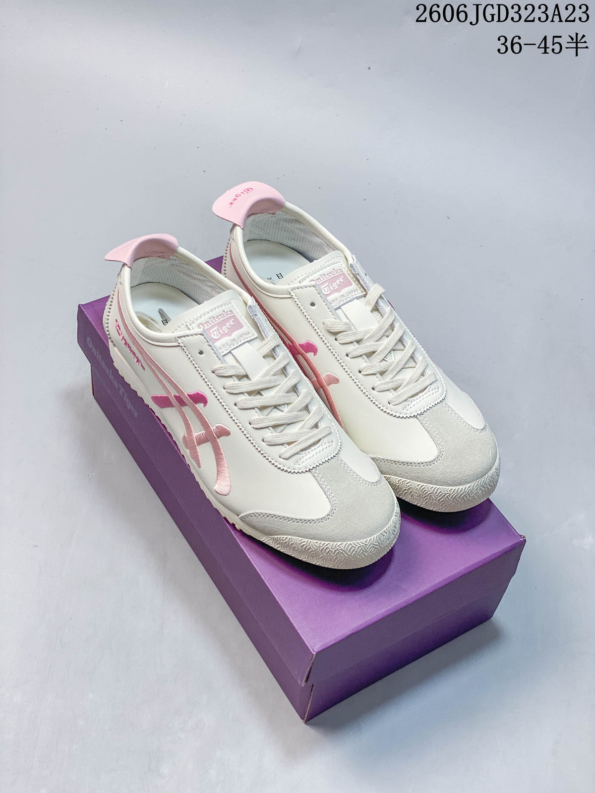 Pair of ivory low-top sneakers with pink side stripes and heel details, shown on a purple box.