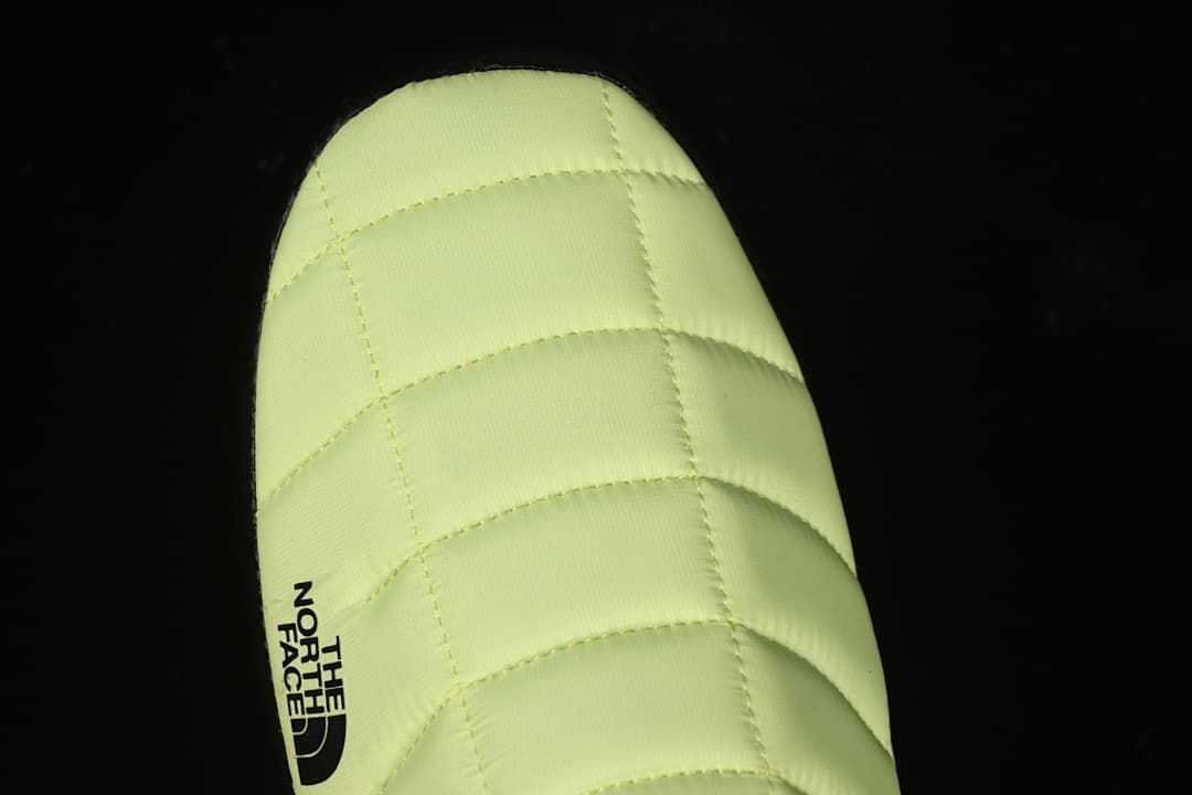 Close-up of the quilted yellow toe with a black logo.