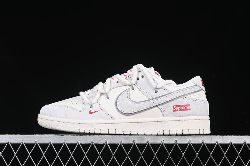 Side view of the white and light gray sneaker with red branding