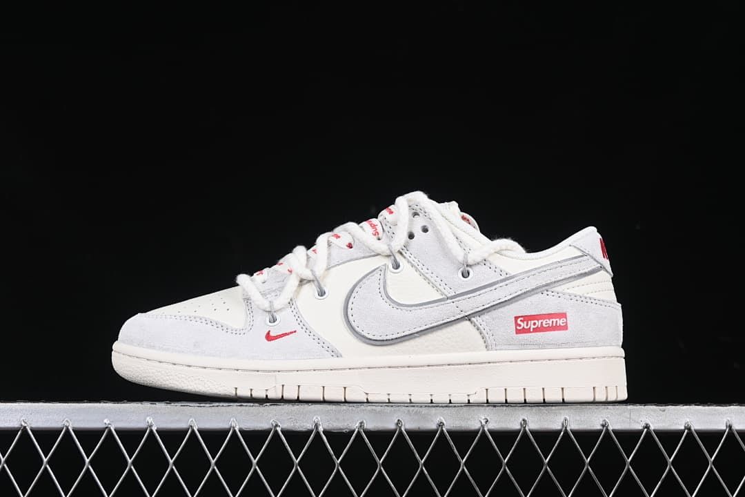 Side view of the white and light gray sneaker with red branding