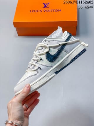 Side profile of a white and gray low-top sneaker with dark blue side detail, rope-style laces, layered panels, and a low rubber sole.