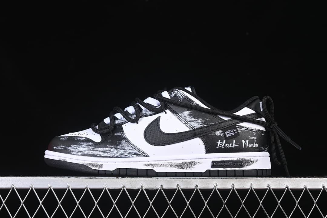 Side view of a black and white low-top sneaker with brushstroke-style graphics