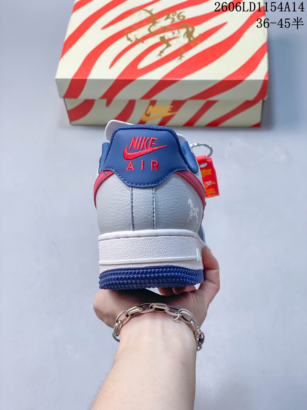 Rear view of a blue and grey Nike Air Force 1 ’07 Low sneaker with red heel lettering.
