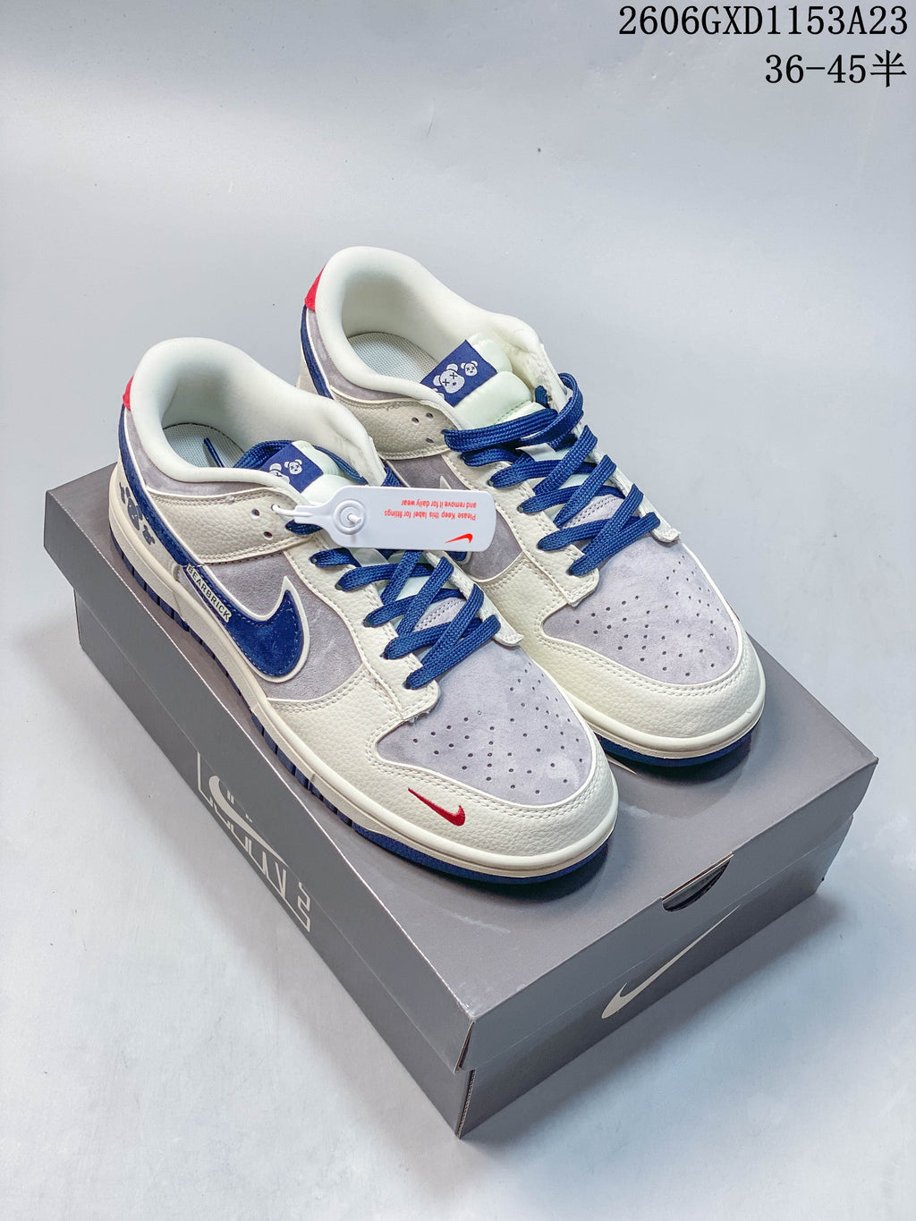 Pair of cream, gray, and blue low-top sneakers with bear graphics, shown on a box.