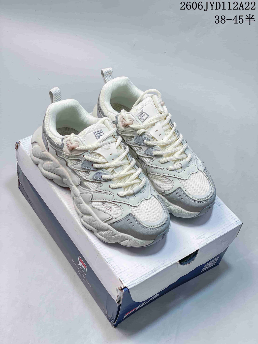 White and gray FILA FUSION Arceus sneakers shown from above on a shoe box