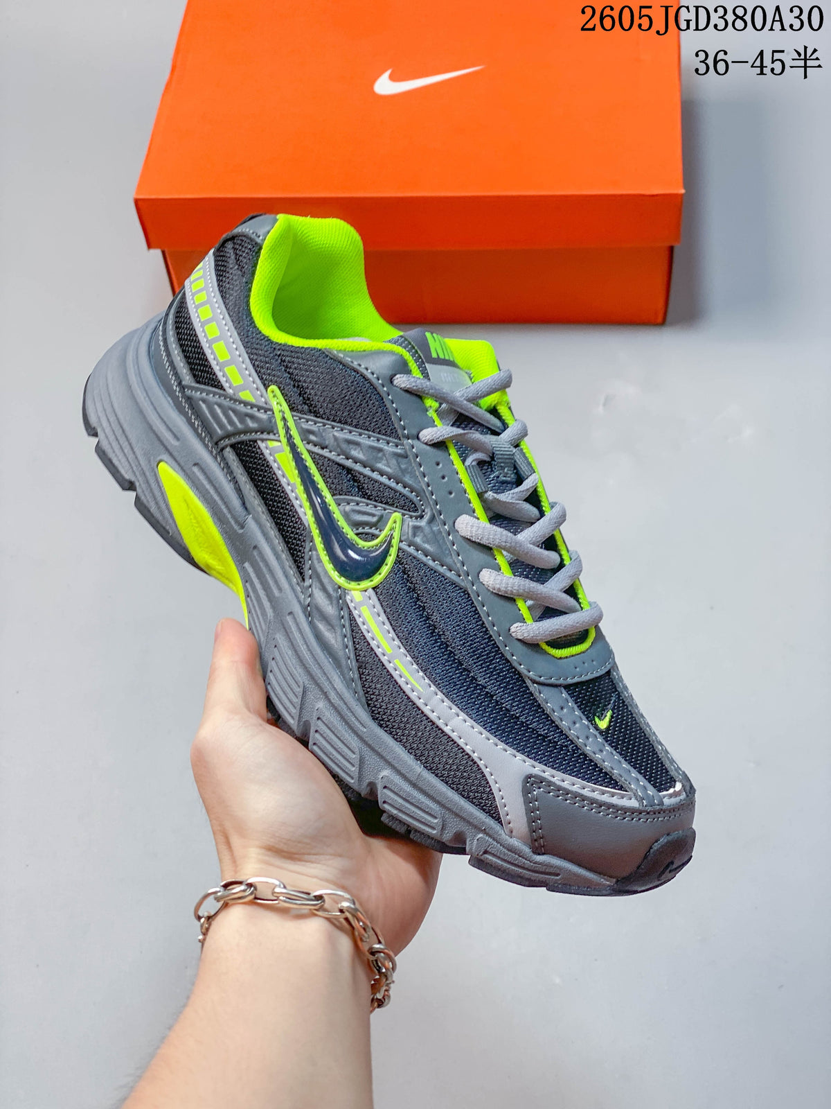 Angled side view of a gray and dark navy Nike sneaker with volt green accents and a sculpted sole.