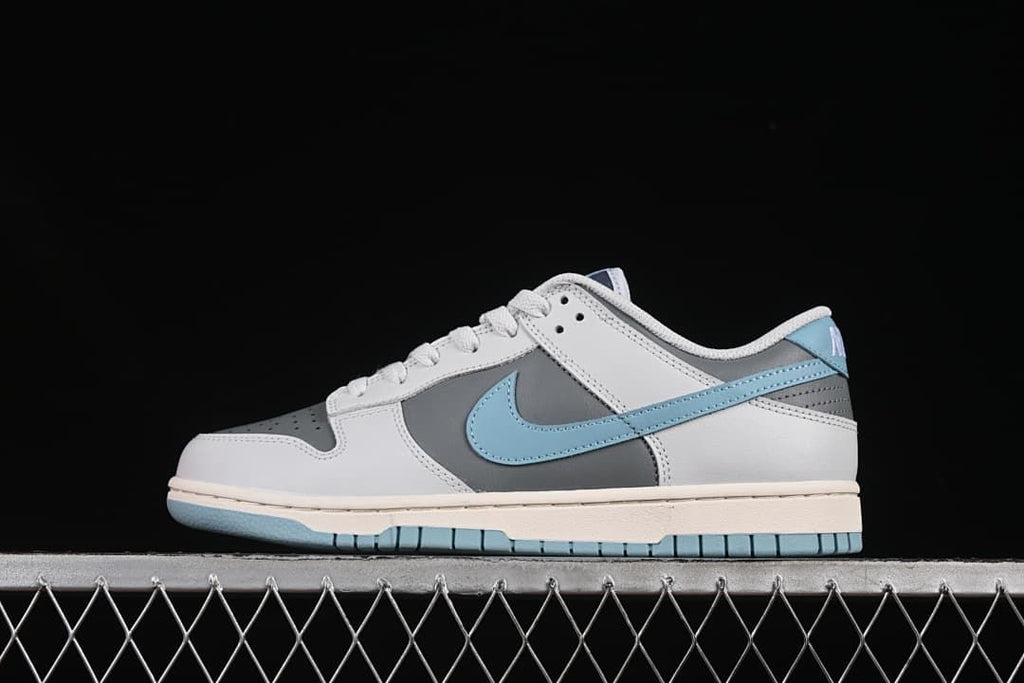 Side view of grey, white, and light blue Nike SB Dunk Low sneakers