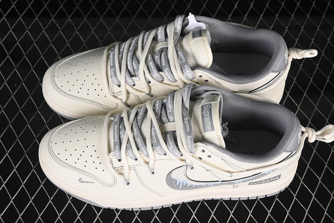 Top view of a pair of off-white and gray low-top sneakers with branded lace details