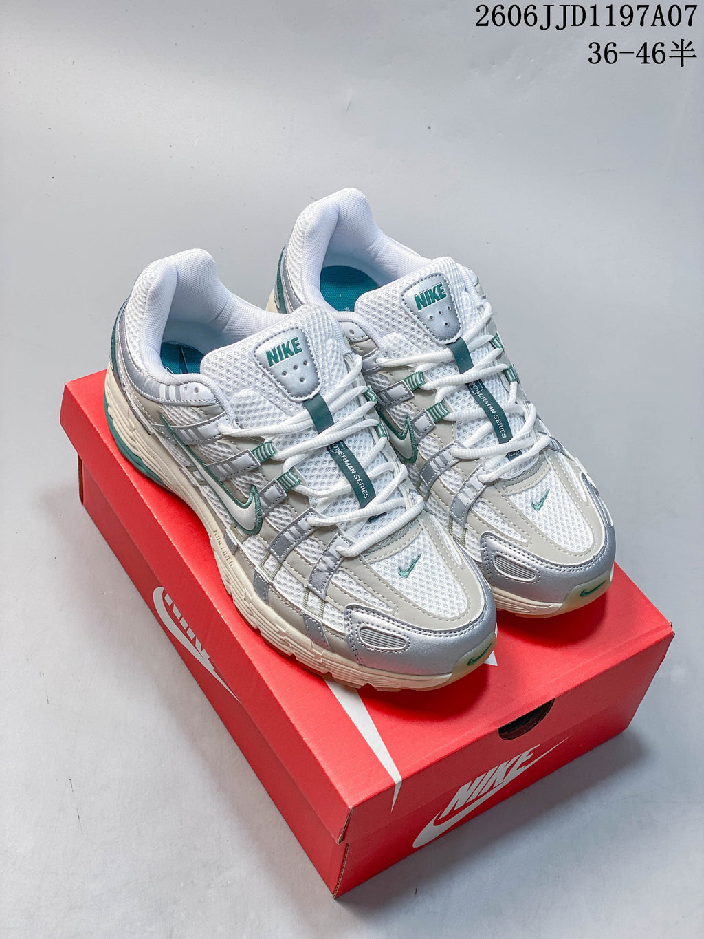 Pair of white, silver, and teal Nike P-6000 Premium sneakers shown on a red shoe box