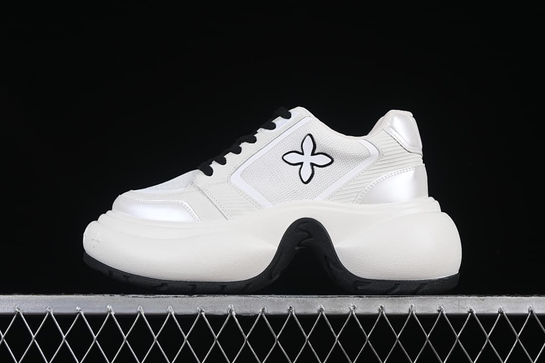 Side view of a white sneaker with a flower-shaped emblem