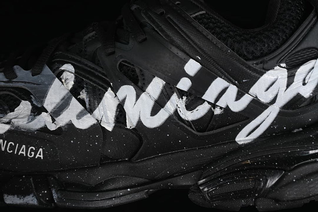 Close-up of white handwriting-style graphics across the black shoe upper.