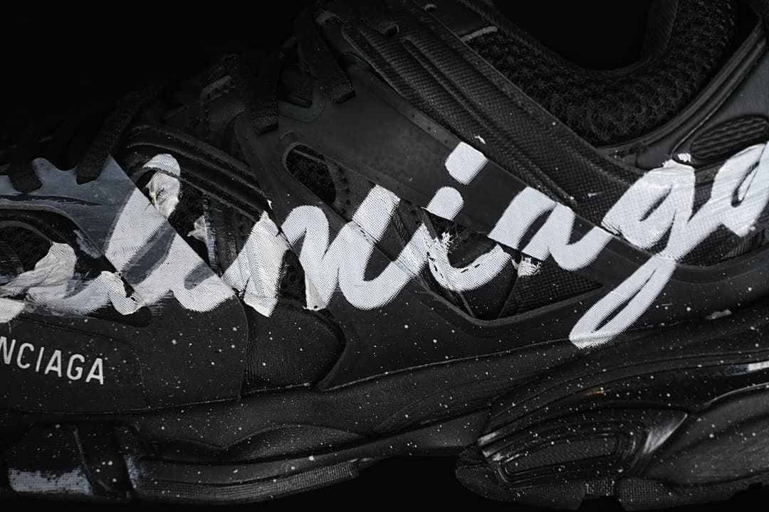 Close-up of white handwriting-style graphics across the black shoe upper.