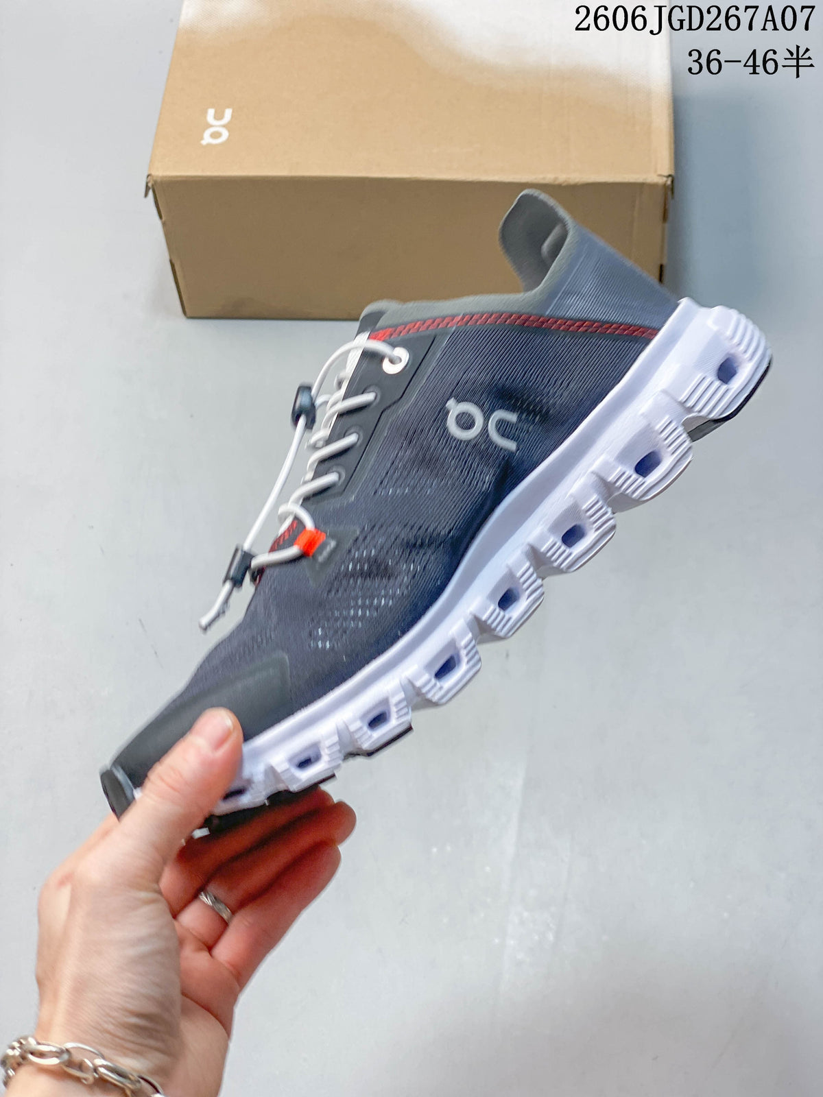 Side view of the gray low-top sneaker with white segmented sole and red detailing.