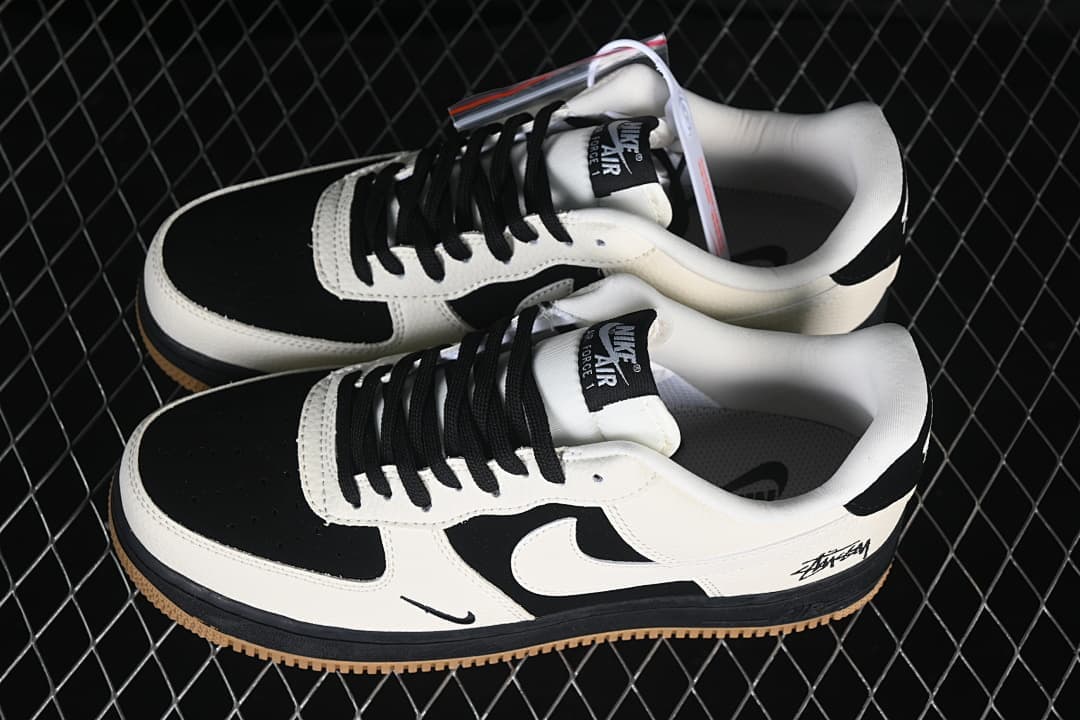 Pair of black, sail, and gum low-top sneakers shown from the side