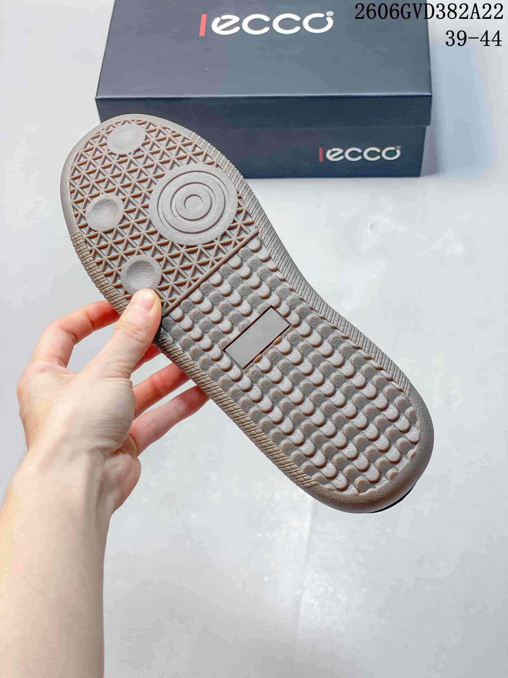 Textured outsole of a gray and navy sneaker, with an ECCO shoebox in the background.