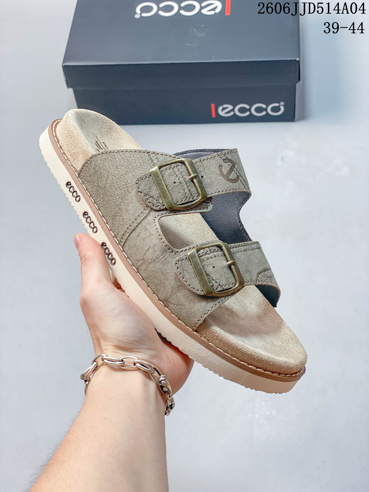 Angled side view of a taupe slide sandal showing two buckle straps and sole branding; image overlay shows 06JJD514A04 and sizes 39–44.