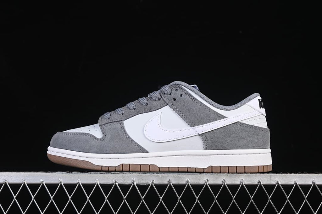 Side view of a white and grey Nike SB Dunk Low shoe with a gum-colored outsole