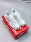 Pair of white Nike Court Borough Low sneakers with pink and mint accents, shown on a red shoe box.