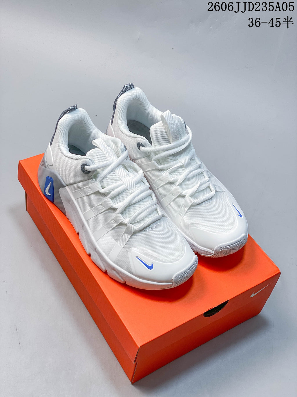 Pair of white Nike Free Metcon 7 training shoes with blue accents, shown from the front on an orange shoebox