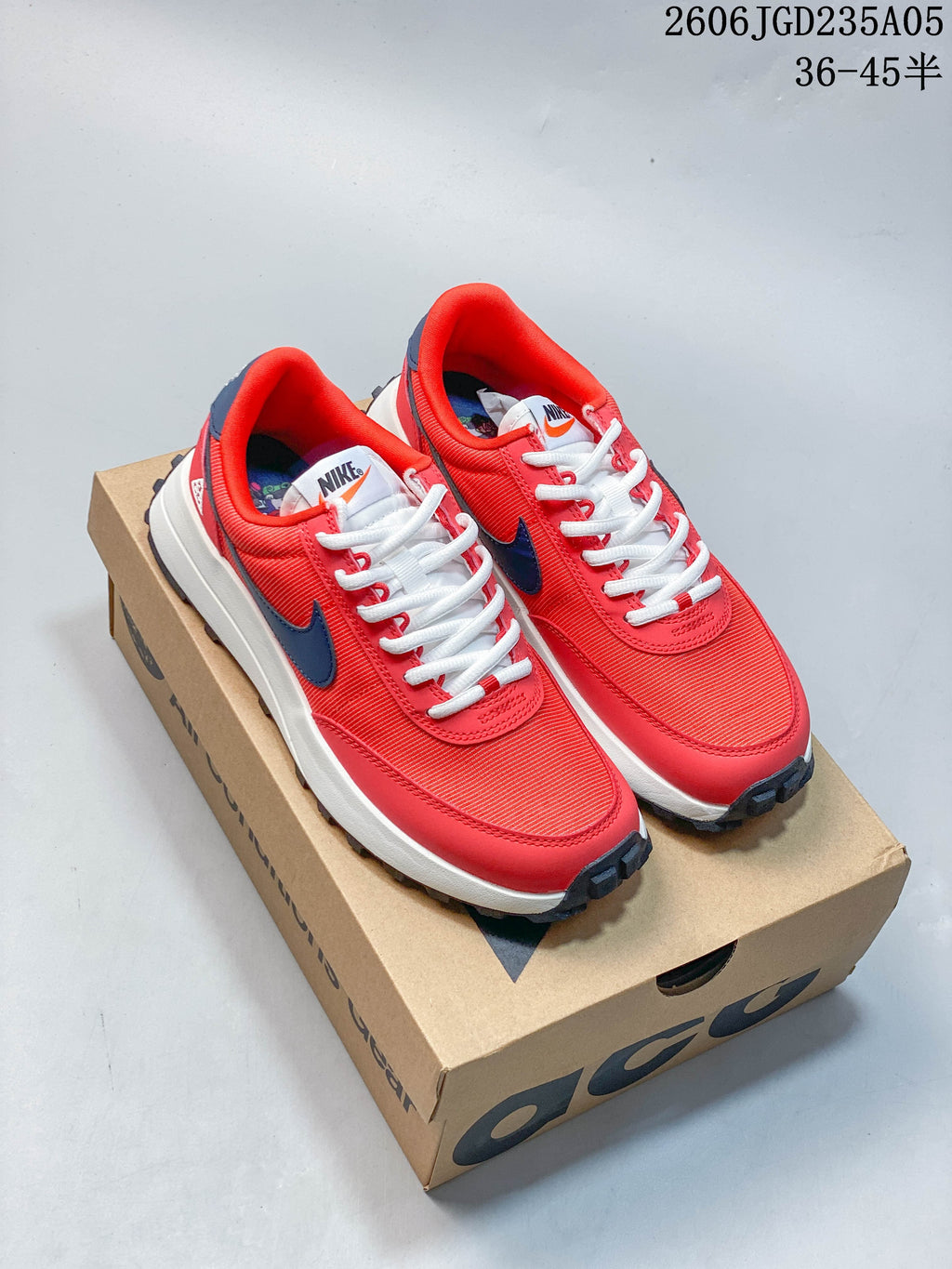 Red Nike ACG LDV shoes with dark blue logos, shown on a box
