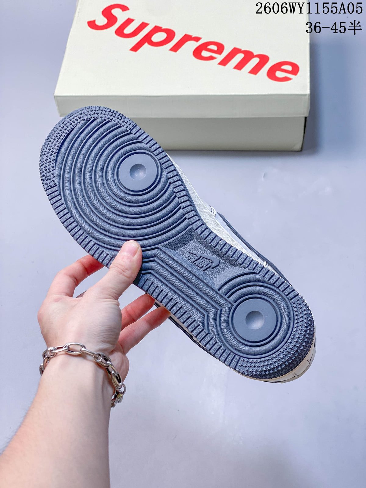 Slate-blue outsole of a low-top sneaker with a Supreme-branded box in the background