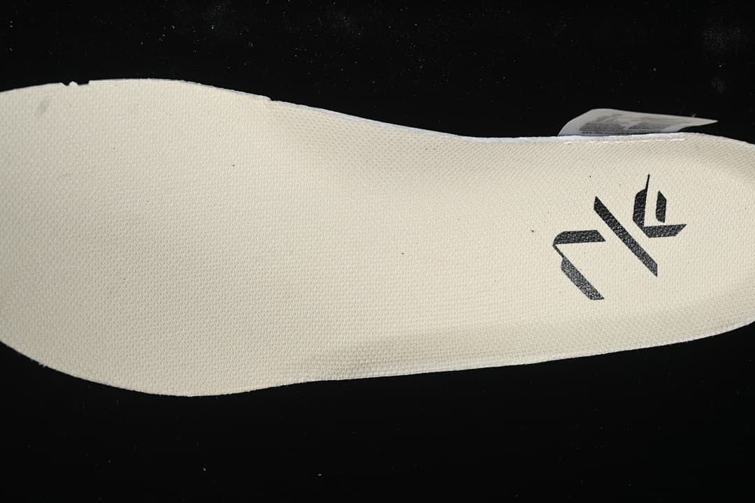 Close-up of a cream-colored shoe insert with a black graphic