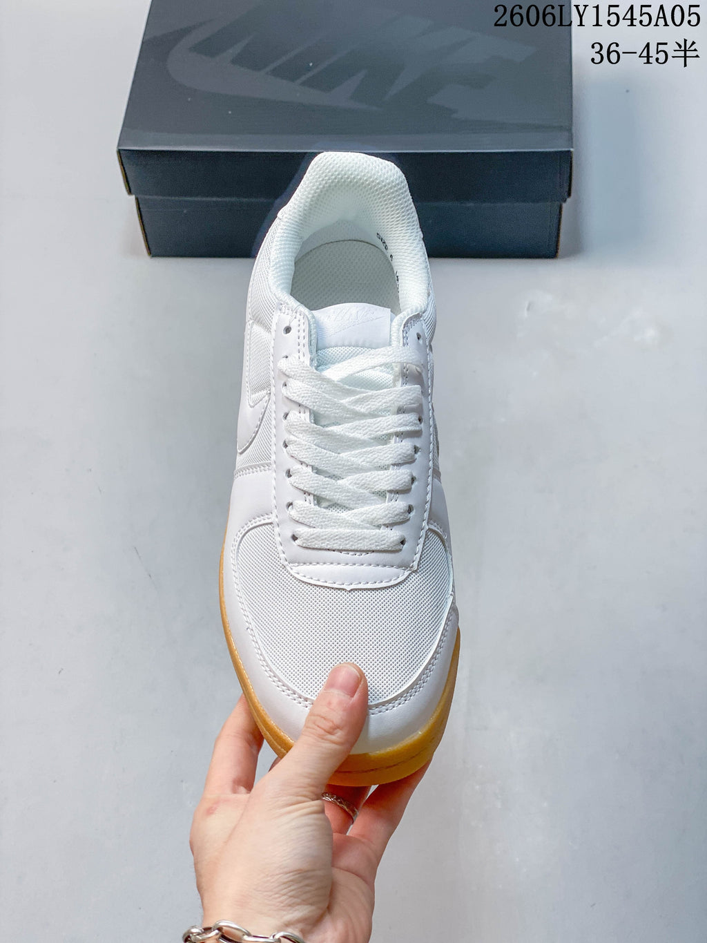 Front view of a white Nike Field General sneaker with white laces and gum-colored sole.