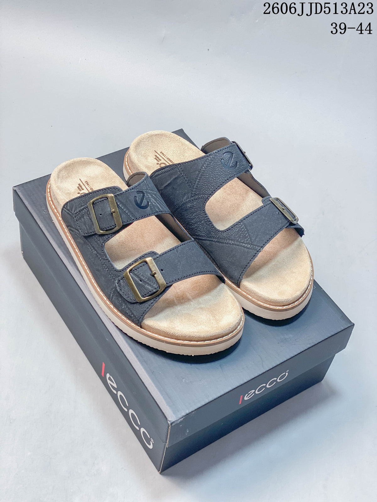 Pair of slate-blue ECCO two-strap slide sandals with light footbeds and buckle details, displayed on a branded box