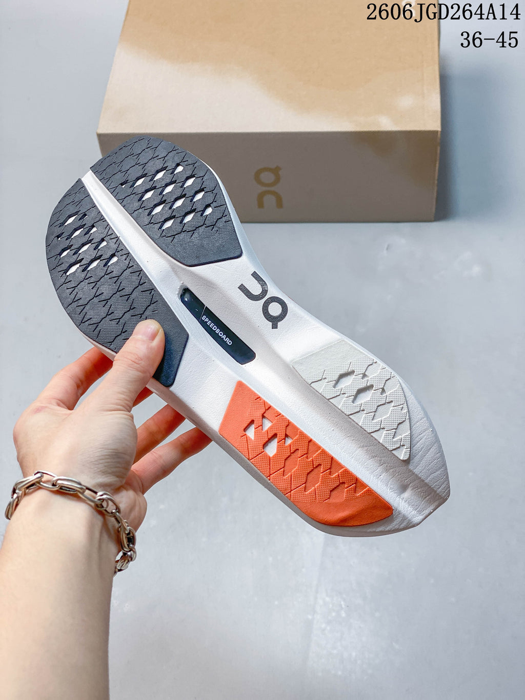 Underside of an On Cloudboom Volt shoe showing patterned outsole sections in dark gray, white, and coral