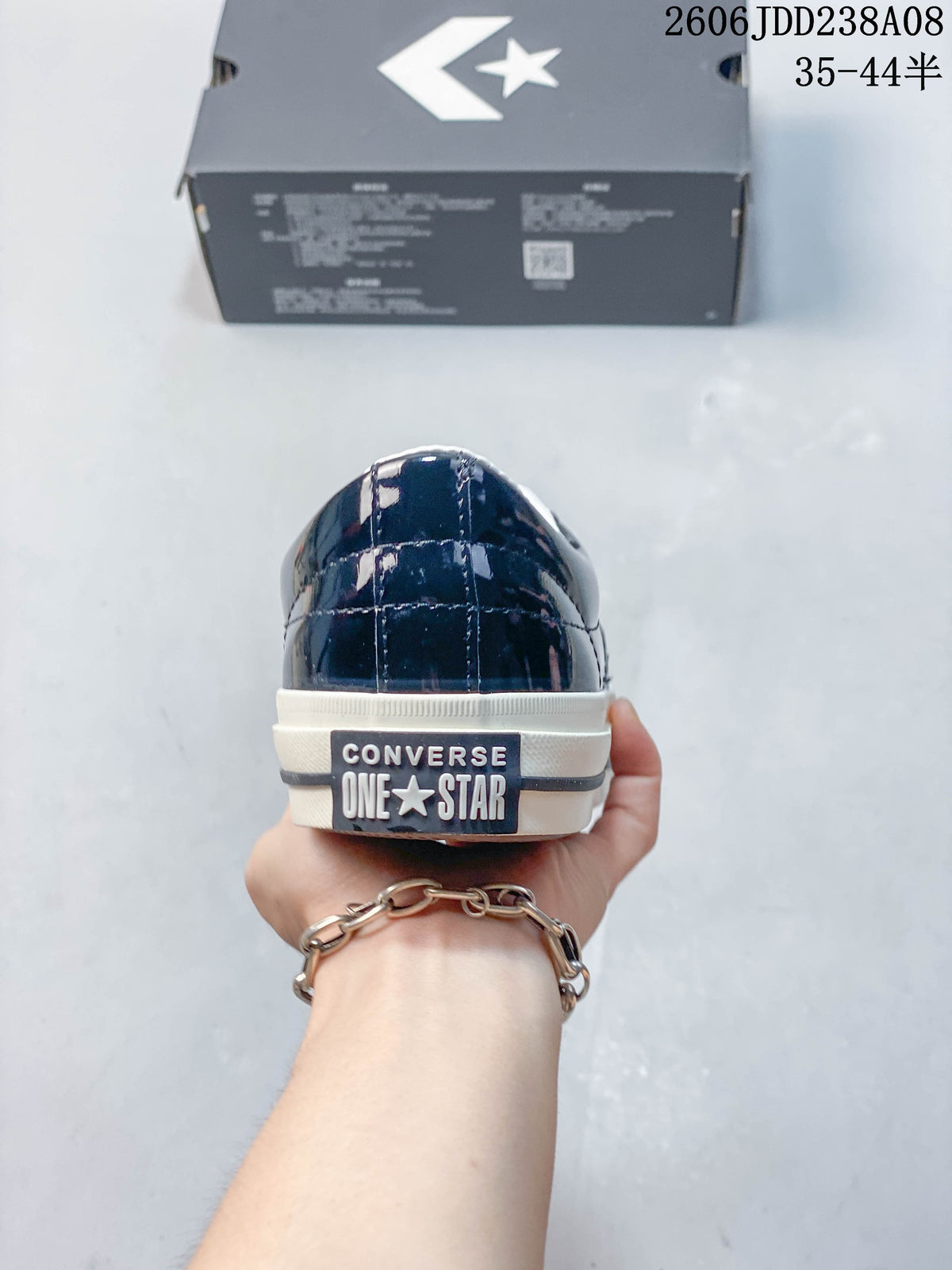 Rear view of a glossy navy sneaker with Converse One Star branding on the heel.