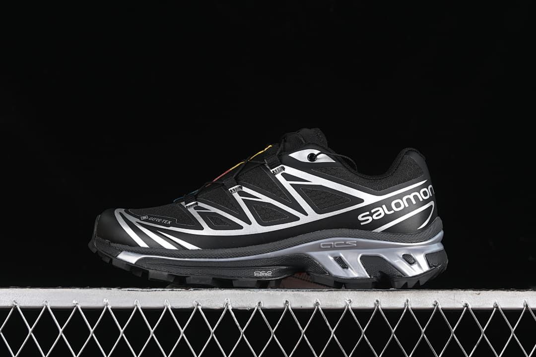 Side view of black and silver Salomon XT-6 GTX sneakers against a dark background.