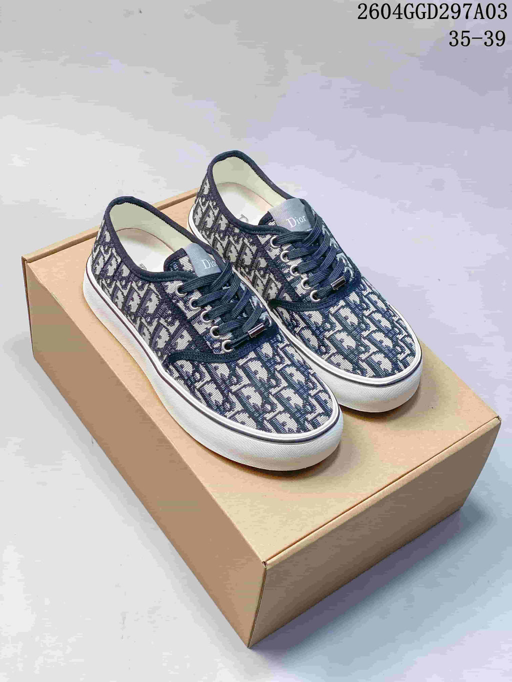 Pair of navy monogram Dior Saltwind sneakers with white soles, shown on a box