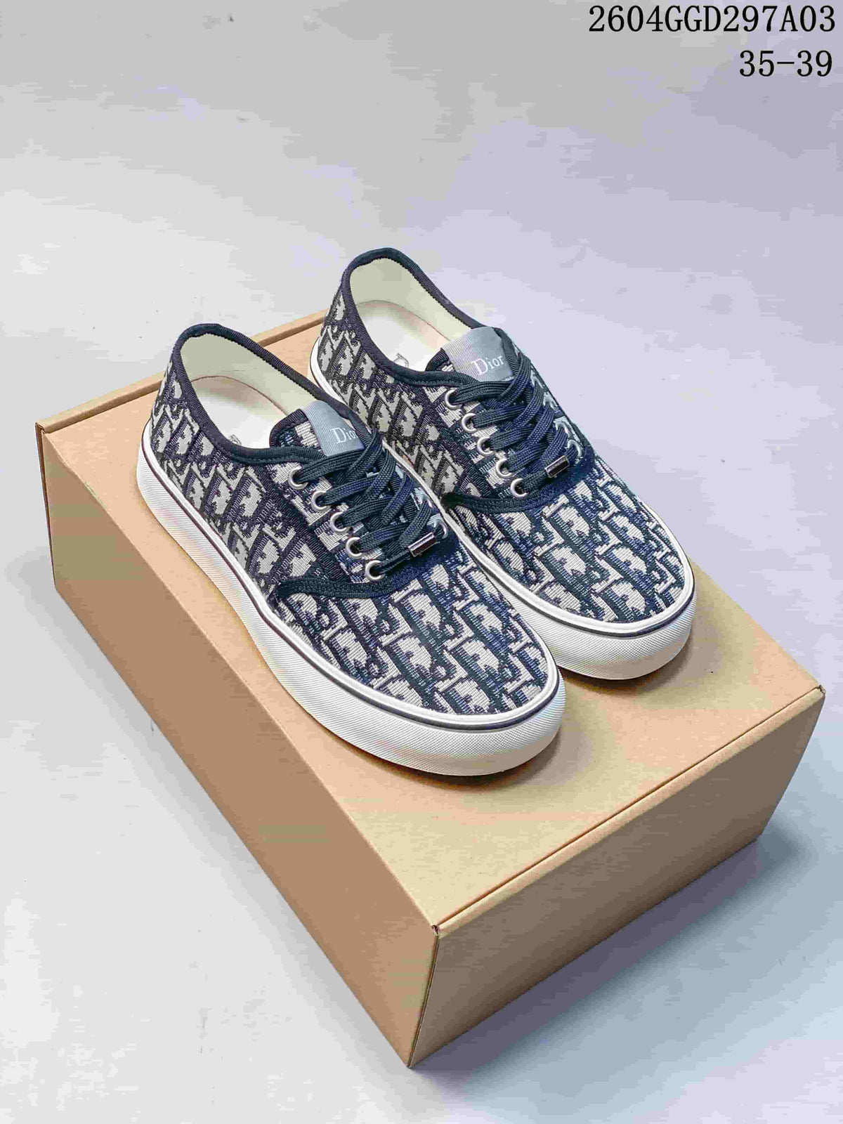 Pair of navy monogram Dior Saltwind sneakers with white soles, shown on a box